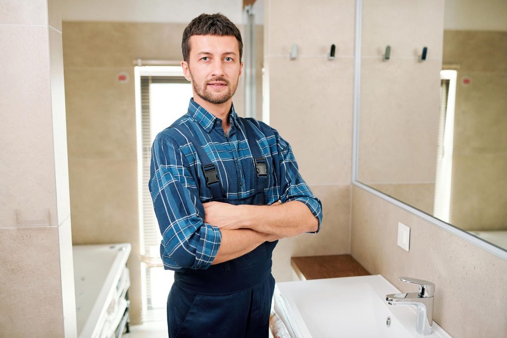 young successful plumber in workwear standing